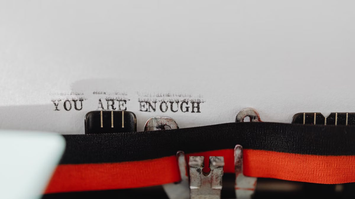 Close-up of a typewriter with the message 'YOU ARE ENOUGH' typed on paper.